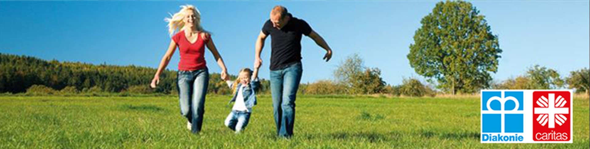 Eltern mit Kind in den Armen auf Wiese